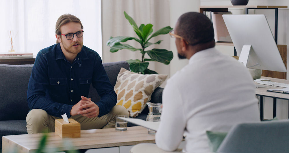 Compassionate therapist speaking with client about addiction recovery