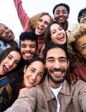 Big group portrait of diverse young people together outdoors - Multiracial happy millennial male and female friends having fun together - Unity and friendship concept - Focus on man in the center